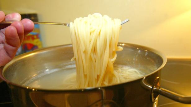 Spaghetti werden aus dem kochenden Wasser genommen