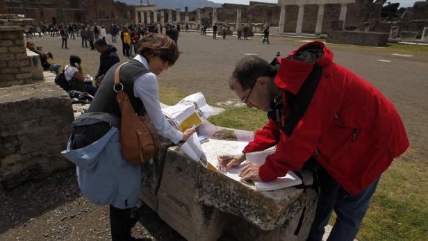 Zwei Touristen betrachten einen Stadtplan in den Ruinen von Pompeji.
