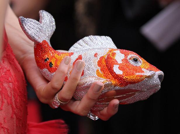 Eine Frau hält eine mit Strasssteinen besetzte Handtasche in Form eines Kois.