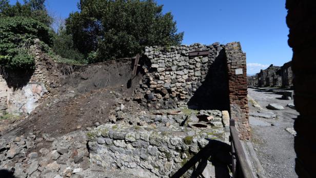 Überreste von Steinmauern in Pompeji unter blauem Himmel.