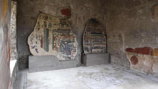 Zwei antike Wandmalereien in einem Raum mit Mosaikboden.