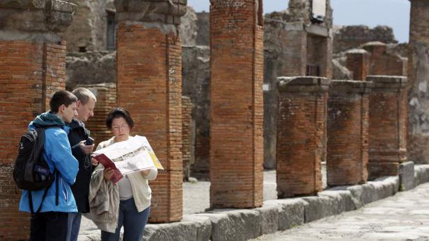 Eine Gruppe Touristen betrachtet eine Karte in den Ruinen von Pompeji.