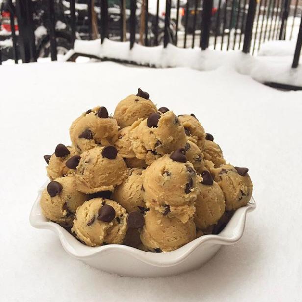 Ein Schale voller roher Keksteigkugeln mit Schokoladenstückchen im Schnee.