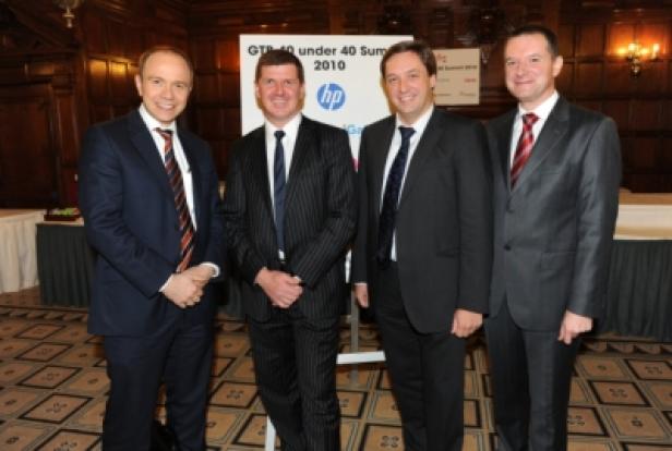 Vier Männer in Anzügen posieren vor einem Schild für den „GTI 40 under 40 Summit 2010“.