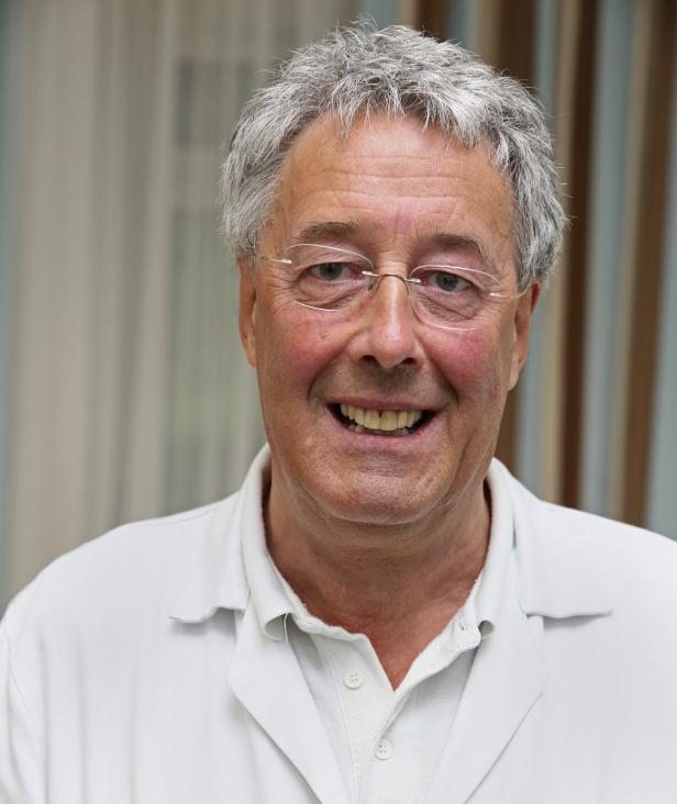Dr. Reinhard Preusser Ein lächelnder älterer Mann mit Brille und weißem Arztkittel.
