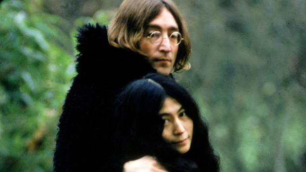 John Lennon umarmt Yoko Ono im Freien.