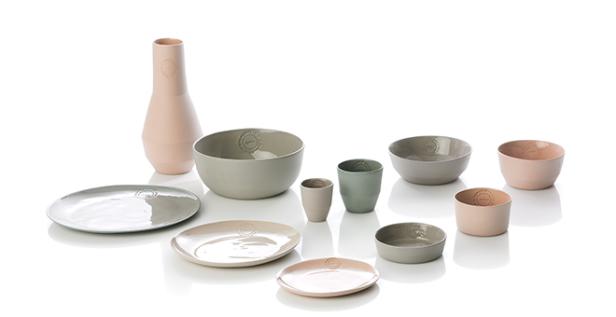 Eine Sammlung von Tellern, Schüsseln, Tassen und einer Vase in verschiedenen Pastellfarben auf einem weißen Hintergrund.
