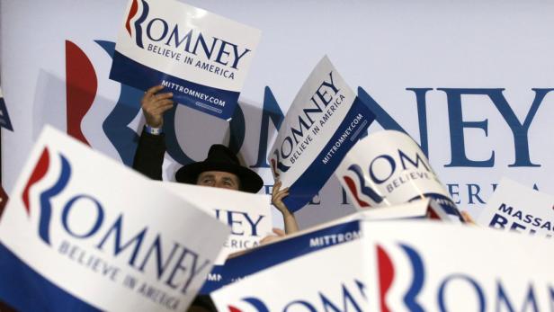 Eine Person hält Schilder mit der Aufschrift „Romney. Believe in America“ hoch.