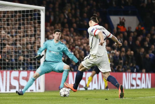 Ein Fußballspieler schießt den Ball auf das Tor, während der Torwart versucht, ihn abzuwehren.