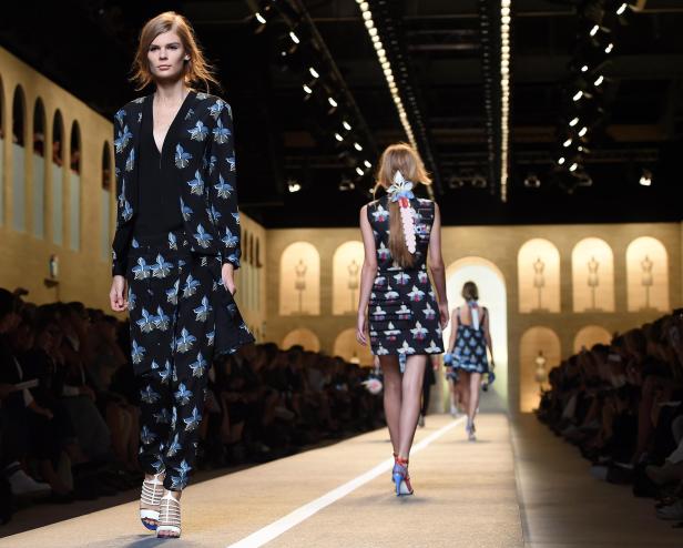 Models präsentieren Mode auf einem Laufsteg mit floralen Mustern.