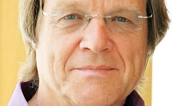 Porträt eines Mannes mit Brille und blonden Haaren.