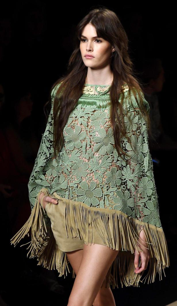 Eine Frau trägt ein grünes Spitzenoberteil mit Fransen.