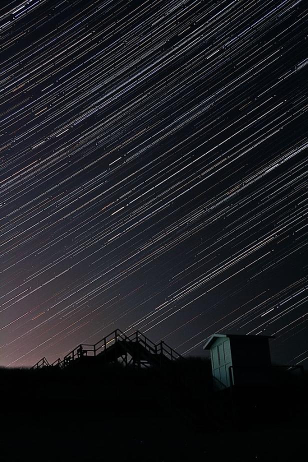 Sternenspuren ziehen sich über eine Treppe und ein kleines Gebäude.