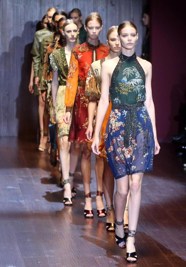 Models präsentieren farbenfrohe, gemusterte Kleider auf einem Laufsteg.