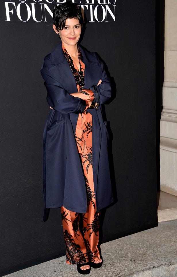 Audrey Tautou trägt einen marineblauen Mantel über einem orangefarbenen Pyjama mit Blumenmuster.