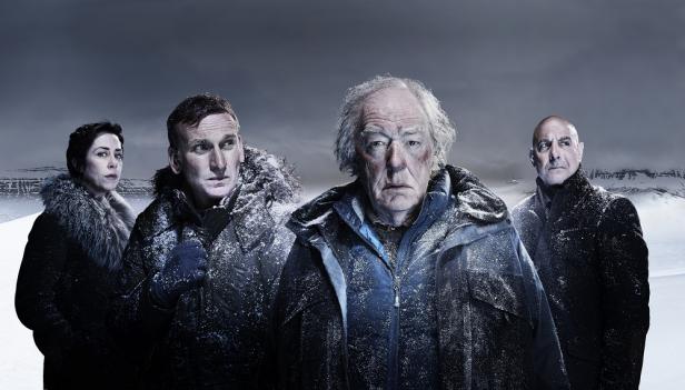 Vier Schauspieler, darunter Christopher Eccleston und Michael Gambon, stehen vor einer verschneiten Landschaft.