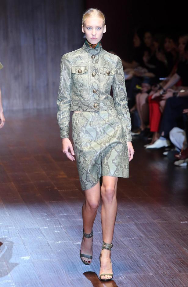 Eine Frau präsentiert ein Outfit mit Schlangenmuster auf einem Laufsteg.