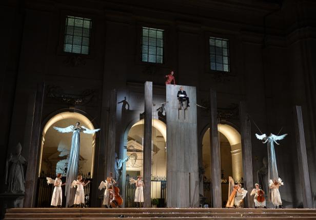 Eine Theaterszene mit als Engel verkleideten Musikern und zwei schwebenden Figuren.