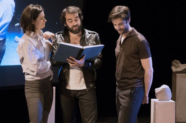 Drei Schauspieler proben ein Stück mit einem Drehbuch in der Hand.