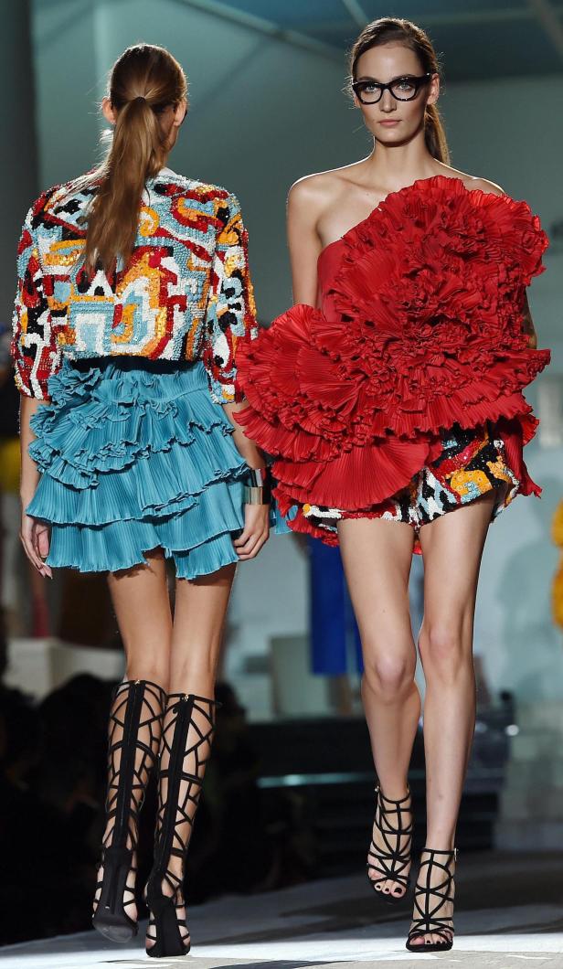 Zwei Models präsentieren farbenfrohe Mode und hohe, schwarze Gladiator-Sandalen auf dem Laufsteg.