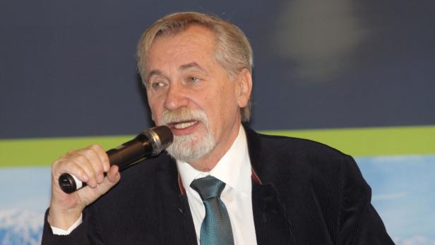 Ein Mann mit Bart hält ein Mikrofon und spricht.