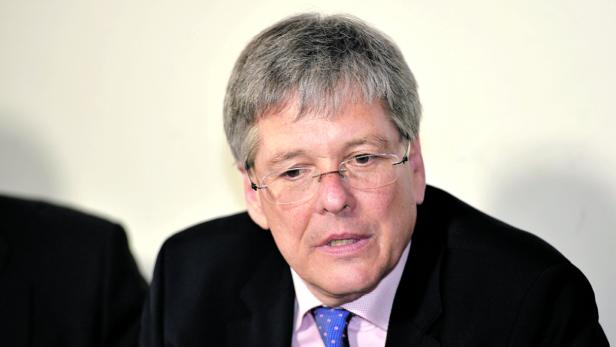 Ein Mann mit Brille, Anzug und Krawatte blickt nach links.