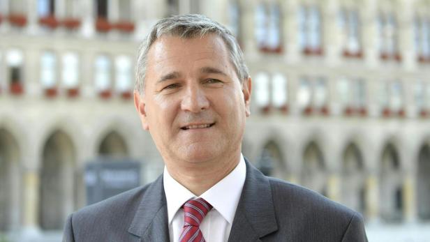 Ein Mann im Anzug mit Krawatte vor einem Gebäude.