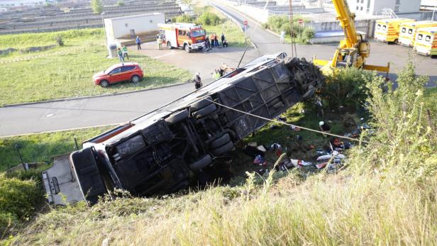 Ein Bus liegt nach einem Unfall in einem Graben, ein Kran ist zur Bergung vor Ort.