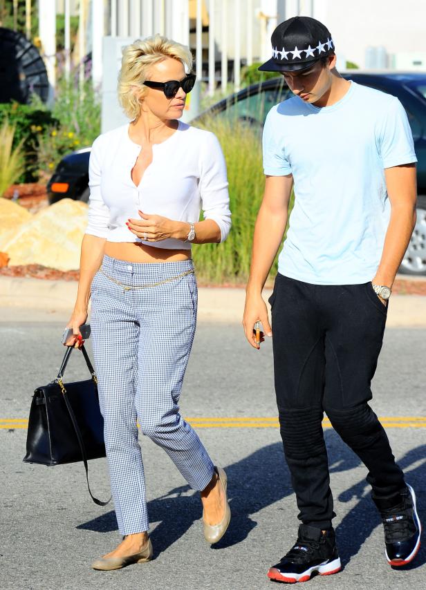 Pamela Anderson geht mit einem jungen Mann auf der Straße entlang.