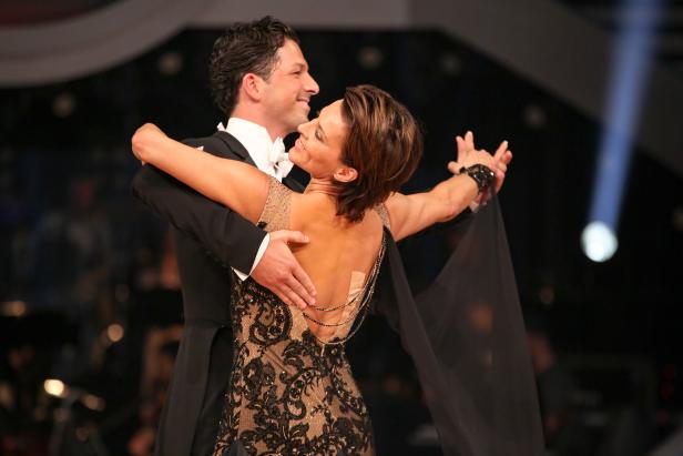 Ein Tanzpaar umarmt sich und lächelt auf einer Bühne.