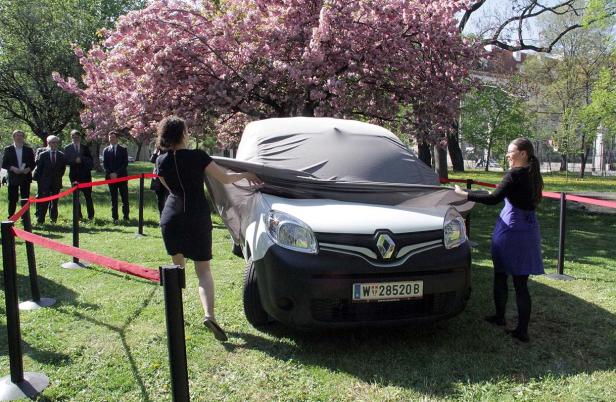 Zwei Frauen enthüllen ein Auto der Marke Renault vor einer Gruppe von Männern.