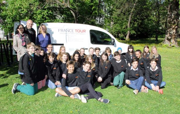 Eine Gruppe von Schülern posiert vor einem „France Tour“-Van.
