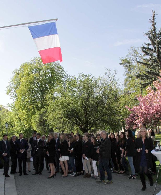 Eine Gruppe von Menschen steht unter der französischen Flagge in einem Park.