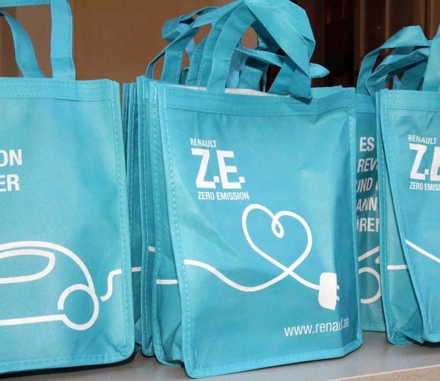 Mehrere hellblaue Stofftaschen mit dem Renault Z.E. Zero Emission Logo stehen auf einem Tisch.