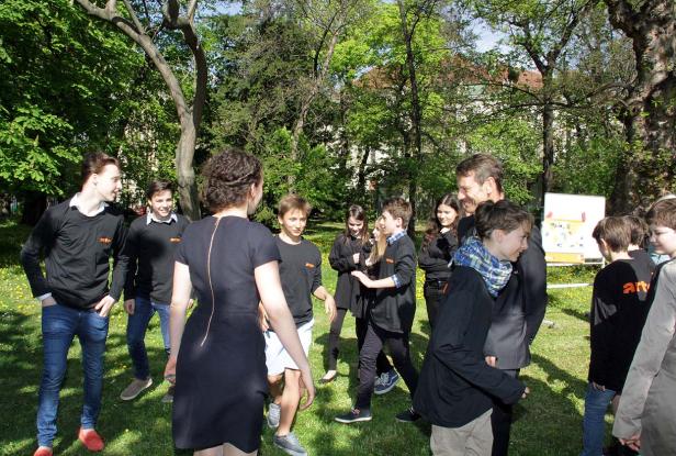Eine Gruppe von Jugendlichen steht mit einem Mann in einem Park zusammen.