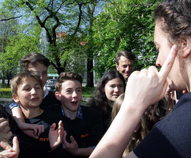 Eine Gruppe von Jugendlichen steht im Freien, möglicherweise in einem Park, und unterhält sich.