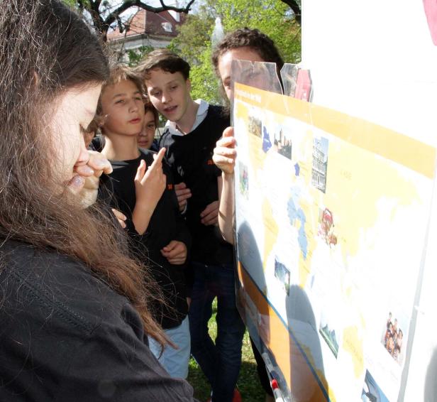 Eine Gruppe von Jugendlichen betrachtet eine Weltkarte im Freien.