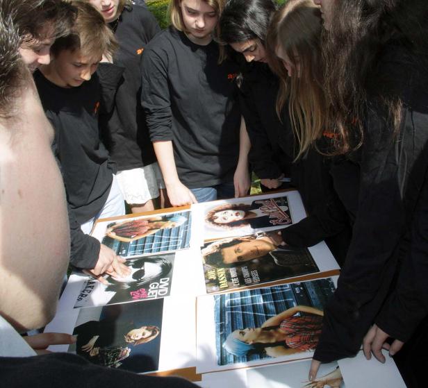 Eine Gruppe von Jugendlichen betrachtet Fotos von verschiedenen Personen.