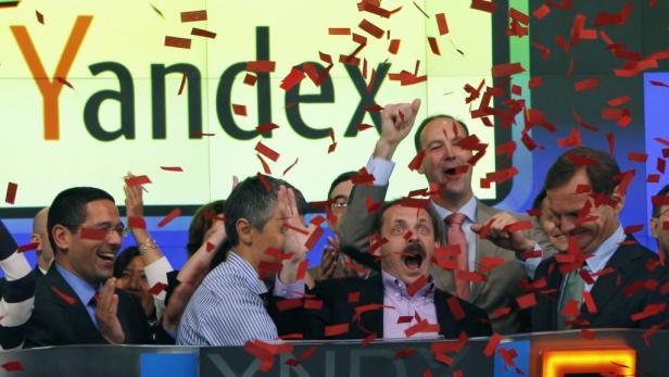 Eine Gruppe von Menschen feiert mit Konfetti vor dem Yandex-Logo.