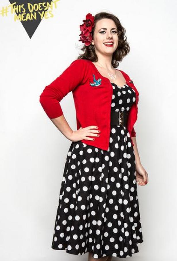 Eine Frau im Retro-Look mit einem gepunkteten Kleid und einer roten Strickjacke.