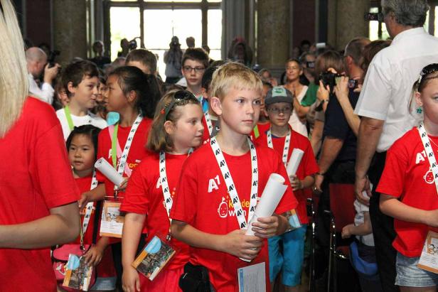 Eine Gruppe Kinder in roten T-Shirts mit A1-Logo steht in einem Raum.