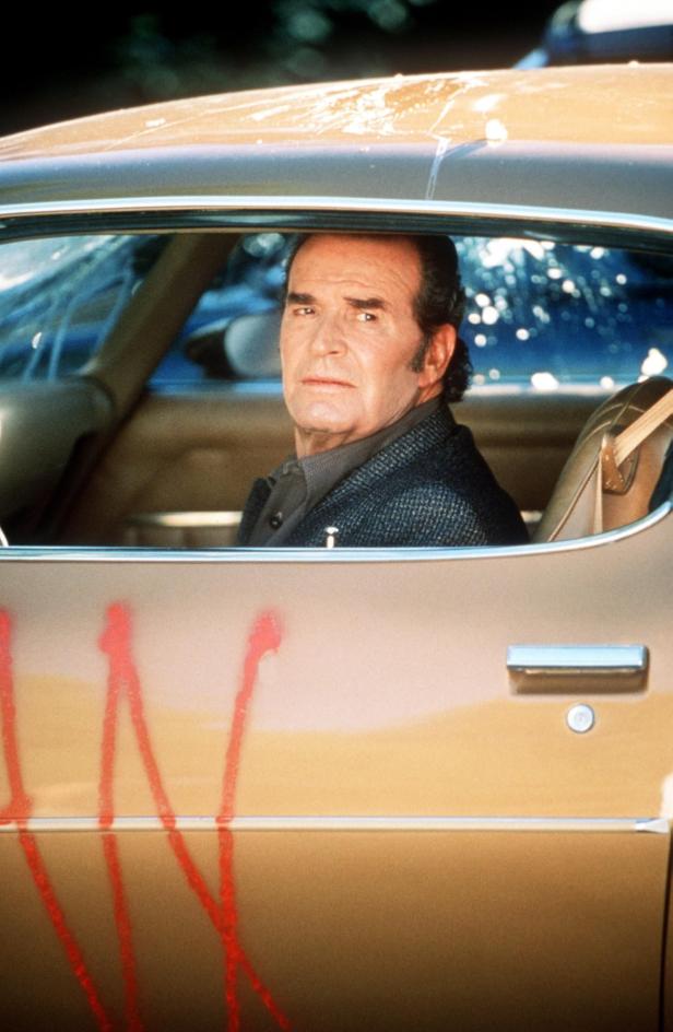 James Garner sitzt in einem Auto, dessen Tür mit roter Farbe beschmiert ist.