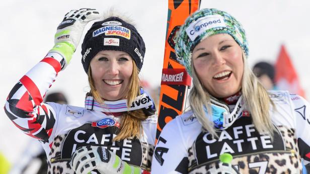 Zwei Skirennläuferinnen in ihren Rennanzügen lächeln in die Kamera.