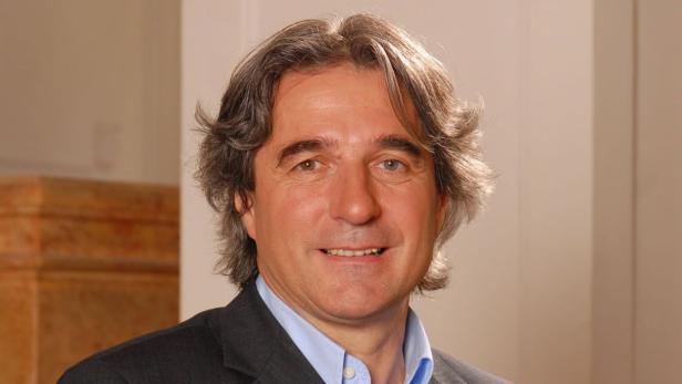 Ein lächelnder Mann mit heterochromen Augen in einem Anzug.