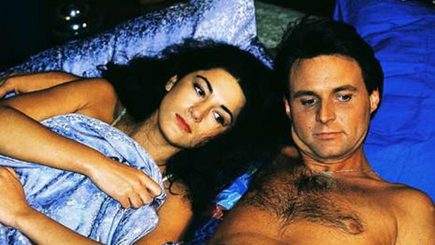 Ein Paar liegt zusammen unter einer blauen Decke.