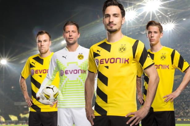 Vier Fußballspieler von Borussia Dortmund posieren vor einem Stadion.