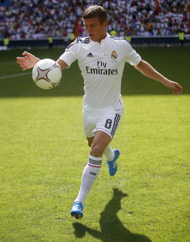 Toni Kroos im Trikot von Real Madrid mit einem Fußball auf dem Rasen.
