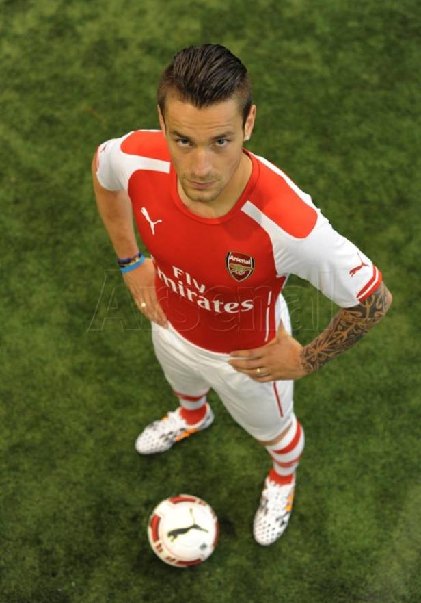 Ein Fußballspieler im rot-weißen Arsenal-Trikot steht mit einem Fußball auf dem Rasen.
