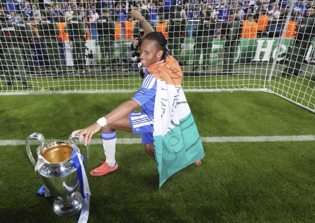 Didier Drogba mit der Flagge der Elfenbeinküste und der Champions-League-Trophäe.