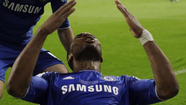 Ein Fußballspieler im blauen Trikot jubelt mit erhobenen Armen.